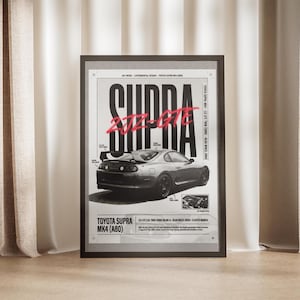 May include: Framed art print of a Toyota Supra MK4 (A80) car. The print has a black and white design with the word "SUPRA" in large, bold letters and "2JZ-GTE" in red. The car is shown in a side profile.