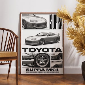 May include: A framed black and white poster featuring a silver Toyota Supra MK4. The poster includes multiple images of the car, the word "SUPRA" in bold letters, and the Toyota logo. The poster is displayed in a room with a wooden chair and decorative plants.