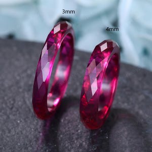 May include: Two vibrant magenta rings with a faceted, geometric surface texture. One ring is labeled 3mm and the other is labeled 4mm, indicating their respective widths. The rings have a translucent appearance and a polished, reflective finish.