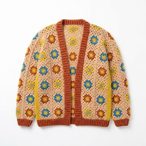 Könnte beinhalten: Beige Häkel-Cardigan mit offenem Frontdesign und farbenfrohem Blumenmuster. Der Pullover hat ein quadratisches Granny-Stich-Design mit braunen, gelben und blauen Akzenten. Die Einfassung und die Kanten sind dunkelbraun.