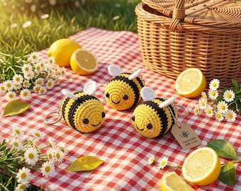 May include: Three crocheted bee keychains with yellow and black yarn bodies, white wings, and black eyes. One bee features a small brown tag with a bee icon and the text Handmade with Love. The bees are arranged on a red and white checkered fabric.