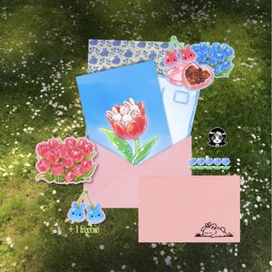 May include: A collection of stickers and cards featuring floral and bunny designs. Includes a pink envelope, a blue card with bunnies in a tulip, and a pink card with a bunny illustration. The stickers include cherries, hearts, and flowers.