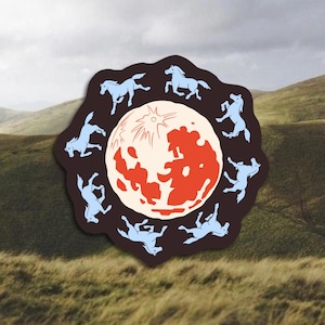 May include: A sticker featuring a central red and cream-colored moon design surrounded by twelve light blue horse silhouettes on a dark brown background. The sticker is set against a backdrop of rolling green hills and a cloudy sky.