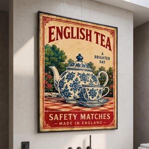 以下が含まれることがあります： English Tea Safety Matchesのヴィンテージ風広告が描かれた長方形の壁掛けポスター。赤と白のチェック柄のテーブルクロスの上に、青と白の花柄のティーポットとティーカップが置かれたデザインで、English Teaという文字が記されています。