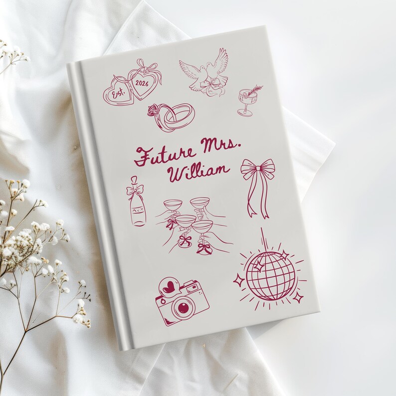 Op de afbeelding: Een wit notitieboek met een bordeauxrode illustratie van bruiloft-thema-iconen, waaronder ringen, champagneglazen en een discobal. De tekst "Future Mrs. William" is geschreven in bordeauxrode letters.