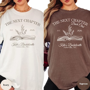 Może przedstawiać: Dwie koszulki, jedna w kolorze kości słoniowej i druga w kolorze espresso, z napisem "THE NEXT CHAPTER" i "Kate's Bachelorette Asheville, NC". Projekt zawiera otwartą książkę z elementami kwiatowymi i rokiem 2026.
