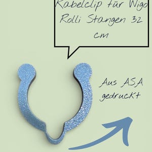 Può includere: Una clip per cavi blu chiaro per barre Wigo Rolli, lunga 32 cm, realizzata in ASA. La clip ha una superficie strutturata e una forma unica, progettata per tenere saldamente i cavi. Il testo nell'immagine dice "Kabelclip für Wigo Rolli Stangen 32 cm".