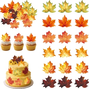 Puede incluir: Una colección de decoraciones de hojas de arce en tonos rojos, naranjas, amarillos y verdes. El conjunto incluye recortes de hojas individuales, tres cupcakes con decoraciones de hojas y un pastel de dos pisos con hojas similares.