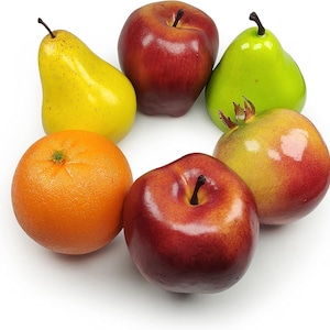 May include: A collection of six artificial fruits arranged in a circle, including a yellow pear, a red apple, a bright green pear, a textured orange, a second red apple, and a pomegranate with a gradient of yellow, orange, and red skin.