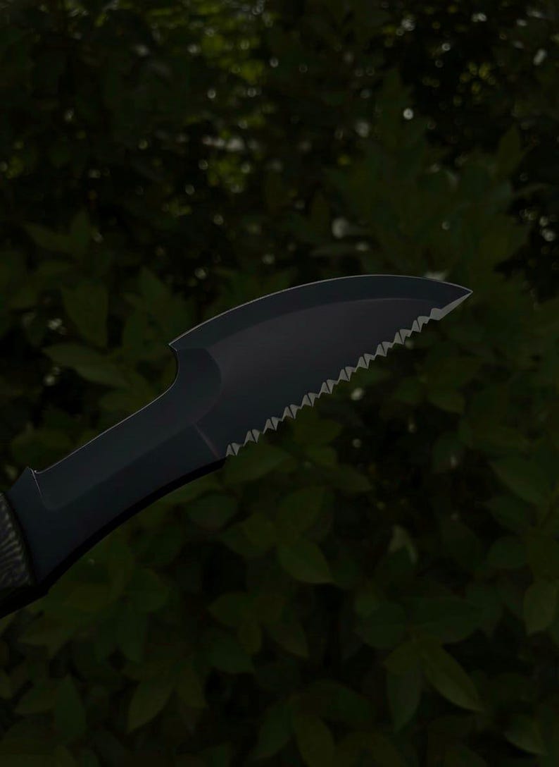May include: A black knife with a serrated edge and a curved blade. The knife has a dark handle and a sharp point. The background is a blurred view of green foliage.