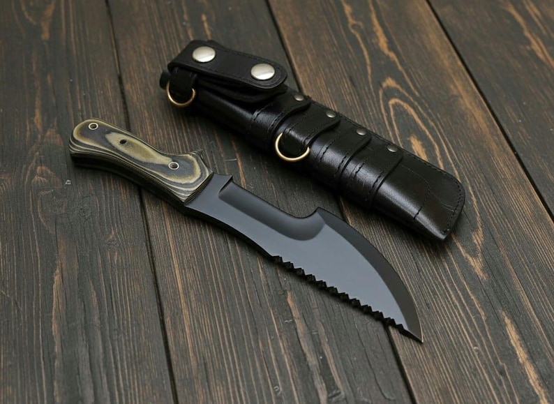 May include: A black hunting knife with a serrated edge and a wooden handle, next to a black leather sheath. The knife has a curved blade and a dark finish. The sheath has a loop and snap closure.