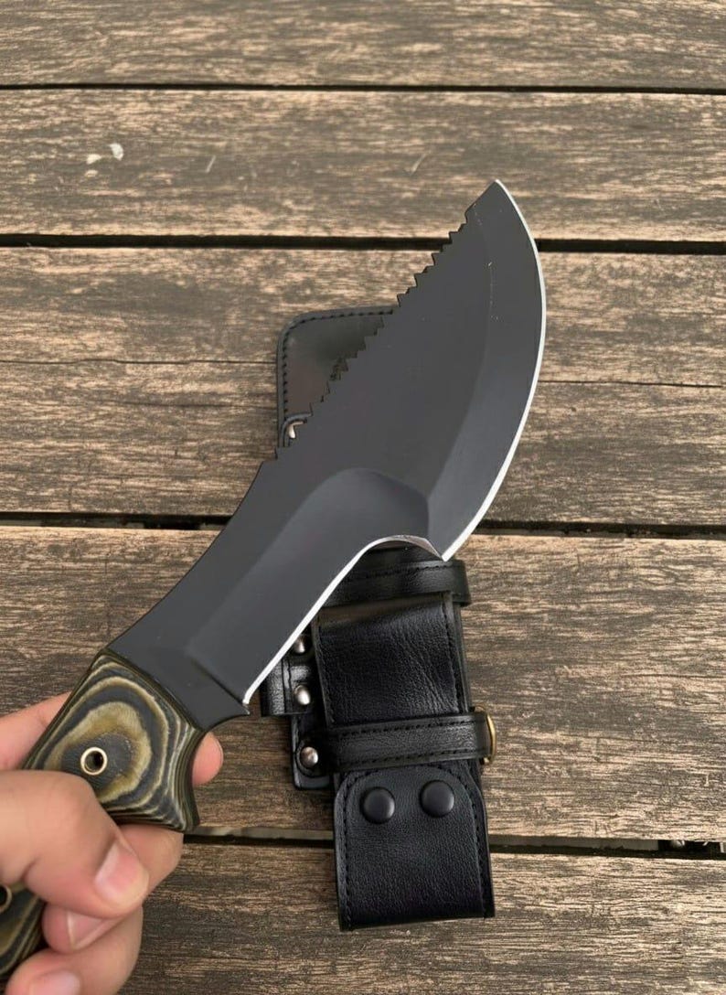 May include: A black survival knife with a partially serrated blade and a wooden handle with a black leather sheath. The knife is designed for outdoor use and survival situations.