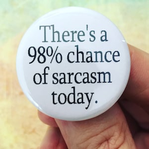 以下が含まれることがあります： 白い丸いボタン。黒い文字で「There's a 98% chance of sarcasm today」と書かれています。ボタンは光沢があり、テキストは中央に配置され、読みやすいです。