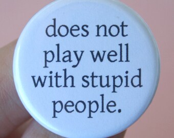 does not play well with stupid people.  1.25 inch pinback button. it's not your fault you are surrounded by idiots.