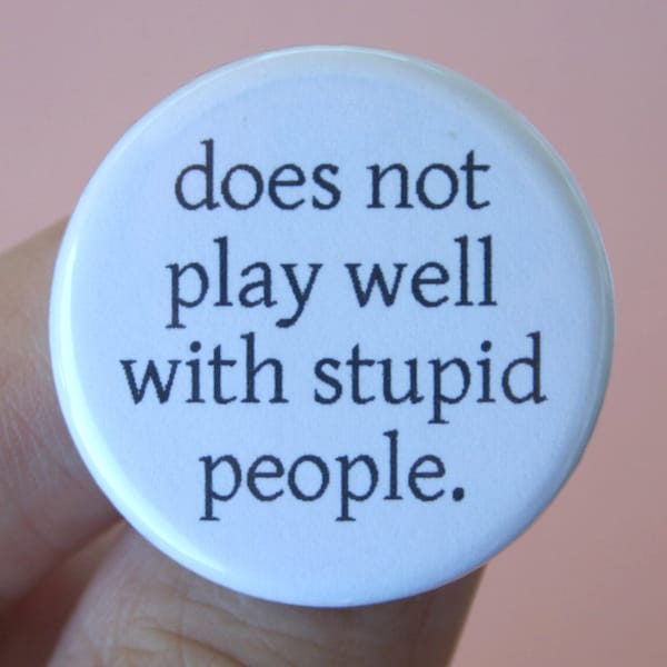 does not play well with stupid people.  1.25 inch pinback button. it's not your fault you are surrounded by idiots.
