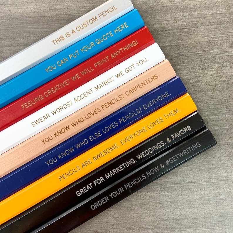 May include: A stack of custom pencils with different coloured paint and gold lettering. The pencils have various sayings on them, including "This is a custom pencil", "You can put your quote here", "Feeling creative? We will print anything!" and "Order your pencils now & #GETWRITING".