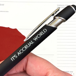 以下が含まれることがあります： シルバーのクリップとスタイラスチップが付いた黒いペン。ペンには「IT'S ACCRUAL WORLD」という文字が側面に刻まれています。