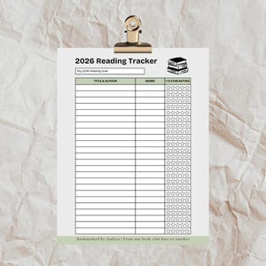 May include: A white 2026 Reading Tracker sheet, clipped to a gold binder clip. The tracker includes sections for title, author, genre, and a 1-5 star rating. The text "2026 Reading Tracker" is at the top. The bottom reads "Bookmarked by Andrea | From one book club host to another."