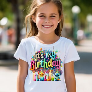Puede incluir: Camiseta blanca con un gr&aacute;fico colorido que dice "It's my Birthday". El dise&ntilde;o incluye velas, globos y personajes de dibujos animados. La camiseta la lleva una ni&ntilde;a.