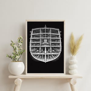 May include: Black and white architectural print of a ship's cross-section, framed in a light wood. The detailed illustration shows the internal structure of the vessel, with multiple decks and internal components. The artwork is displayed on a white wall.