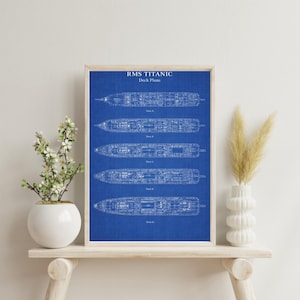 May include: Framed blueprint of the RMS Titanic deck plans, displayed on a wooden shelf. The print features detailed schematics of the ship's decks A, B, C, and D, set against a vibrant blue background. The text "RMS TITANIC Deck Plans" is at the top.