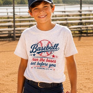May include: A heather grey short-sleeve t-shirt featuring a graphic of a baseball and the text "Baseball run the bases set before you HEBREWS 12:1" in blue and red ink, paired with a navy blue baseball cap with a white baseball icon.
