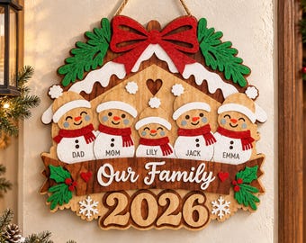 May include: A wooden wall hanging featuring five snowman figures wearing white hats and red scarves, labeled Dad, Mom, Lily, Jack, and Emma. The sign displays the text Our Family 2026, decorated with a red bow, green holly, and white snow accents.