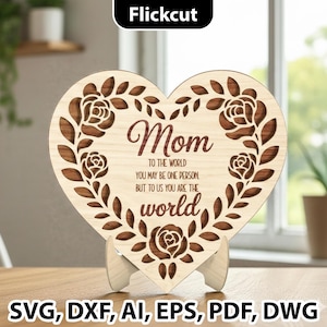 Könnte beinhalten: Herzförmige Holzplakette mit dem Wort „Mom“ und einem floralen Design. Die Plakette enthält den Text „Für die Welt bist du vielleicht eine Person, aber für uns bist du die Welt“.