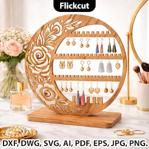 Puede incluir: Un expositor de pendientes de madera con un diseño circular, con cortes florales y múltiples filas de ranuras para pendientes. El expositor contiene varios pendientes. El texto "Flickcut" está en la parte superior. El texto "DXF, DWG, SVG, AI, PDF, EPS, JPG, PNG." está en la parte inferior.