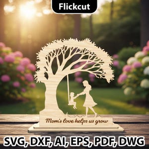 Peut inclure: Décoration en bois en forme d'arbre avec une mère et un enfant sur une balançoire. Le texte "Mom's love helps us grow" est gravé sur la base. La pièce est en bois clair et se détache sur un arrière-plan extérieur flou.
