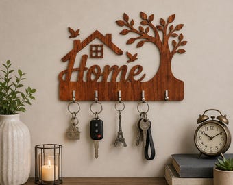 May include: A brown wooden wall-mounted key holder featuring the word Home in cursive script, a house outline, a tree, and two birds. It includes five silver metal hooks holding various keys and keychains, including a car key and Eiffel Tower charm.
