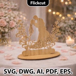 May include: A wooden wedding cake topper featuring a silhouette of a couple embracing, surrounded by decorative floral elements. The topper is made of light-colored wood and has the text "Flickcut" at the top. The bottom of the image has the text "SVG, DWG, AI, PDF, EPS."