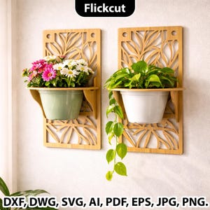 May include: Two bamboo wall planters with floral cut-out designs. One holds pink and white flowers in a green pot, the other has green plants in a white pot. The planters are mounted on a white wall.