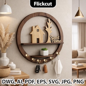 Pode incluir: Uma prateleira de parede redonda de madeira castanha escura com um recorte de casa e árvore, uma pequena prateleira e ganchos para chaves. A prateleira tem as palavras "Sweet Home" e uma pequena planta. Uma chave, um porta-chaves e uma máscara facial penduram-se nos ganchos.