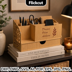 Peut inclure: Un organisateur de bureau en bois brun clair avec plusieurs compartiments pour papeterie, un petit tiroir et le texte gravé au laser Dream Plan Achieve à côté d'un motif de feuille. Les panneaux latéraux présentent des motifs découpés.