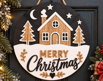 May include: A circular wooden door sign featuring a black background with a layered design of a light wood house, two pine trees, a crescent moon, and stars. The sign includes white snow accents and the text Merry Christmas in black and wood.