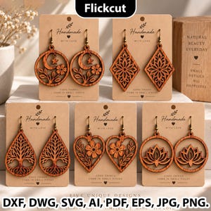 May include: Five pairs of laser-cut wooden earrings displayed on individual brown cardboard cards. The designs include a crescent moon with a star and flowers, a geometric diamond pattern, a tree of life, a heart with flowers, and a lotus flower.