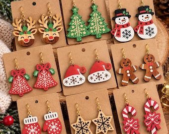 May include: A collection of nine pairs of holiday-themed wooden dangle earrings displayed on brown cards. Designs include reindeer, Christmas trees, snowmen, bells, Santa hats, gingerbread men, mittens, stars, and candy canes with red and white accents.