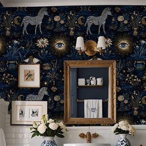 May include: A navy blue bathroom with patterned wallpaper featuring zebras, eyes, and floral designs. The room includes a vanity with a white countertop, a white sink, and gold fixtures. Two blue and white vases with white flowers are on the counter.
