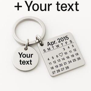Peut inclure: Un porte-clés argenté avec deux étiquettes métalliques. L'une est ronde et indique "Your text". L'autre est carrée et affiche un calendrier d'avril 2015. Le texte "Your date + Your text" est en haut.