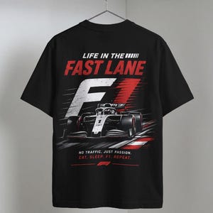Puede incluir: Camiseta negra con un diseño gráfico de un coche de carreras de Fórmula 1 y el texto "LIFE IN THE FAST LANE" en rojo y blanco. La camiseta también incluye el texto "NO TRAFFIC. JUST PASSION. EAT. SLEEP. F1. REPEAT."