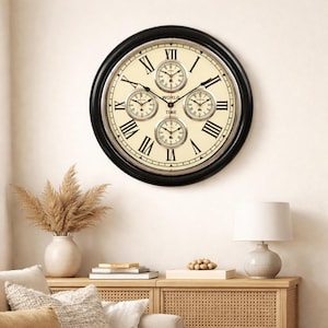May include: A large, round wall clock with a black frame and a cream-coloured face. The clock features Roman numerals and four smaller dials, with the words "WORLD TIME" in the centre. The clock is mounted on a light-coloured wall.