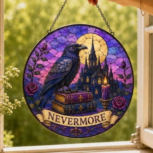 May include: A circular stained glass suncatcher featuring a black raven perched on two stacked books in front of a gothic castle, a full moon, and a lit candle. The design includes purple and blue tones, pink roses, and a banner reading NEVERMORE.