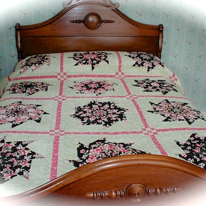 May include: A green and pink quilt with a floral pattern. The quilt is on a wooden bed frame with a headboard.