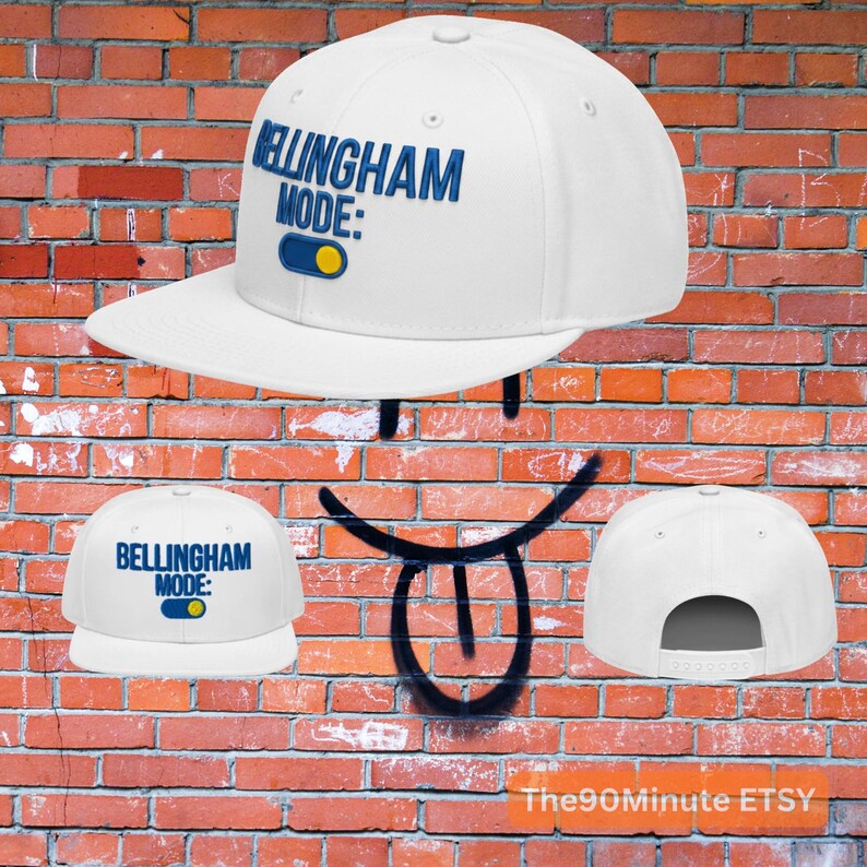 May include: White baseball cap with the text "BELLINGHAM MODE:" in blue. The design includes a blue and yellow toggle switch graphic. The cap has a flat brim and a snapback closure.