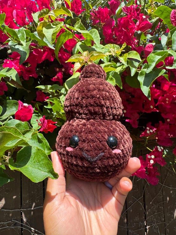 A hand-crocheted poop emoji plush — genuinely handmade, tactile, and absurdly charming as a desk companion or white elephant gift.