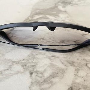 Puede incluir: Gafas con montura negra de dise&ntilde;o elegante y moderno. Las gafas est&aacute;n plegadas, mostrando las monturas oscuras y las varillas finas. Las lentes son transparentes y la est&eacute;tica general es minimalista y elegante.