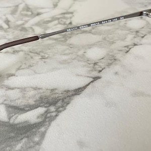 May include: Close-up of Ray-Ban Erika sunglasses. The sunglasses have a brown frame and gradient lenses. The temples are a dark brown color and connect to the lenses with silver hinges. The model number is visible on the frame.