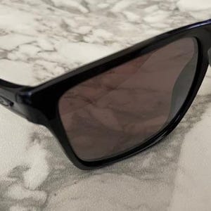 May include: Black sunglasses with dark tinted lenses. The sunglasses have a rectangular frame and a sleek, modern design. The arms curve slightly for a comfortable fit. The lenses appear to be polarized, offering protection from the sun.