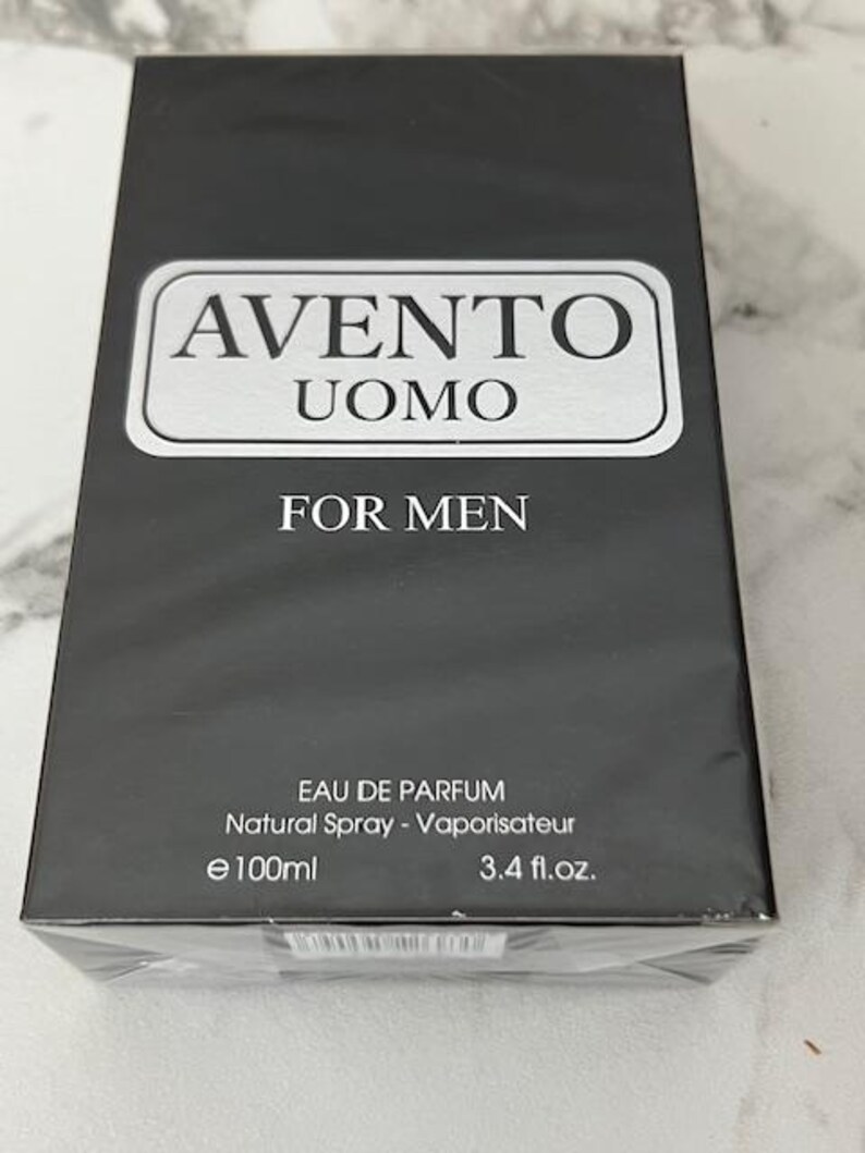 K&ouml;nnte beinhalten: Schwarzer rechteckiger Karton mit "AVENTO UOMO FOR MEN" Eau de Parfum. Die Schachtel hat ein silbernes rechteckiges Etikett mit dem Markennamen und Produktnamen. Der Inhalt betr&auml;gt 100 ml.